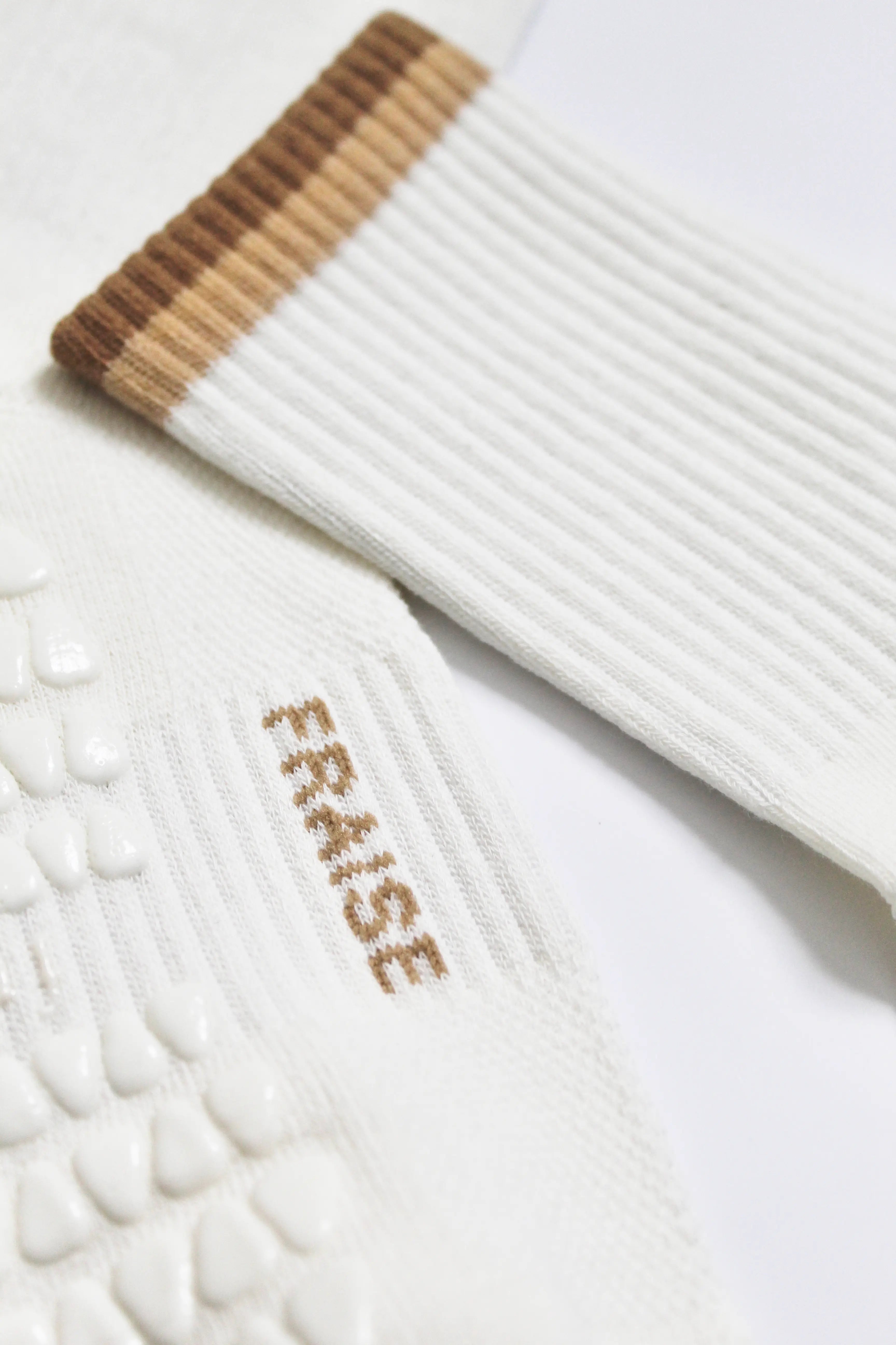 White pilates grip socks with caramel ribbed cuffs and 'FRAISE' branding