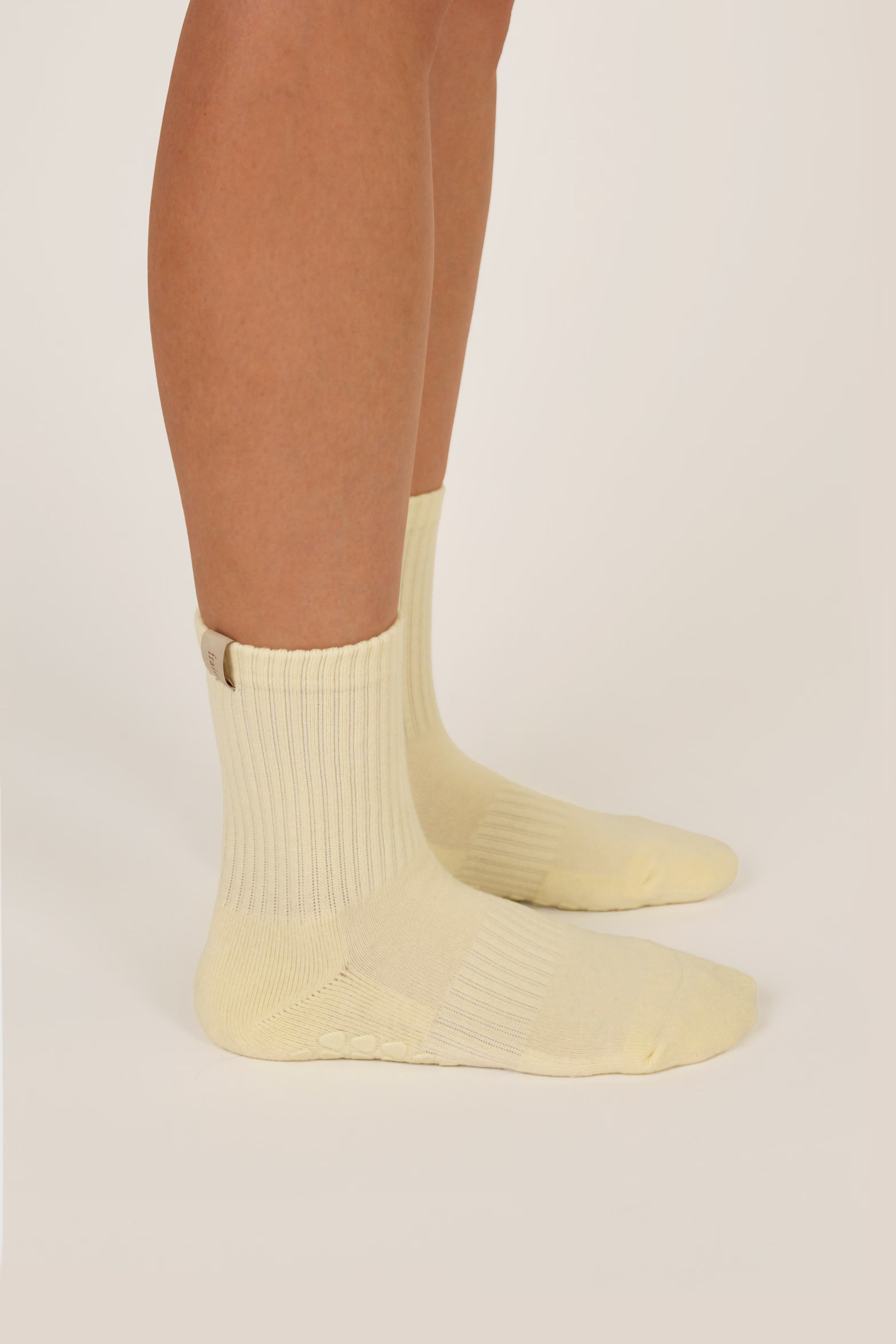 Light butter yellow reformer grip socks on a pale background