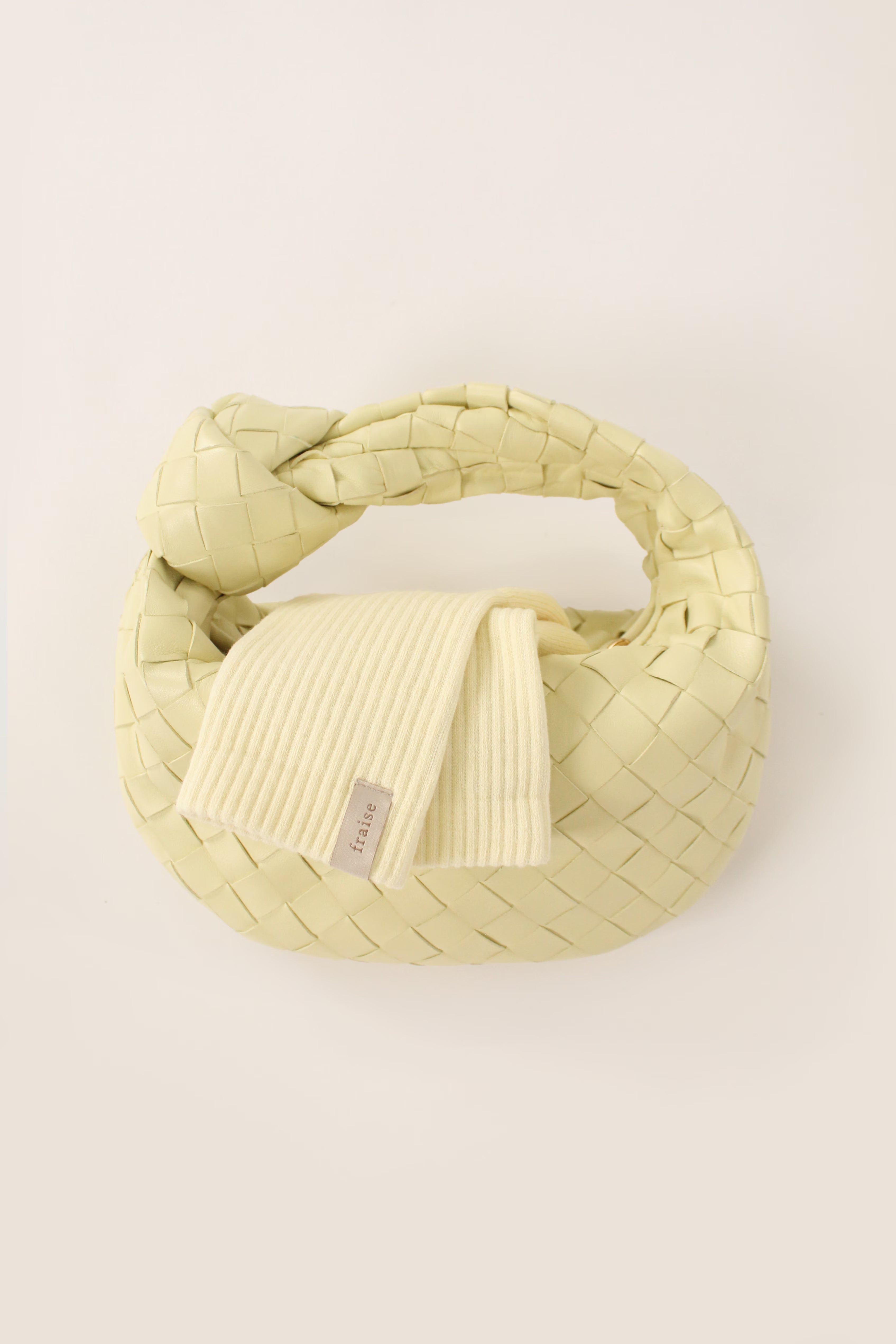 A pale yellow grip sock with the Fraise tag on it inside a Bottega Veneta small jodie intrecciato handbag