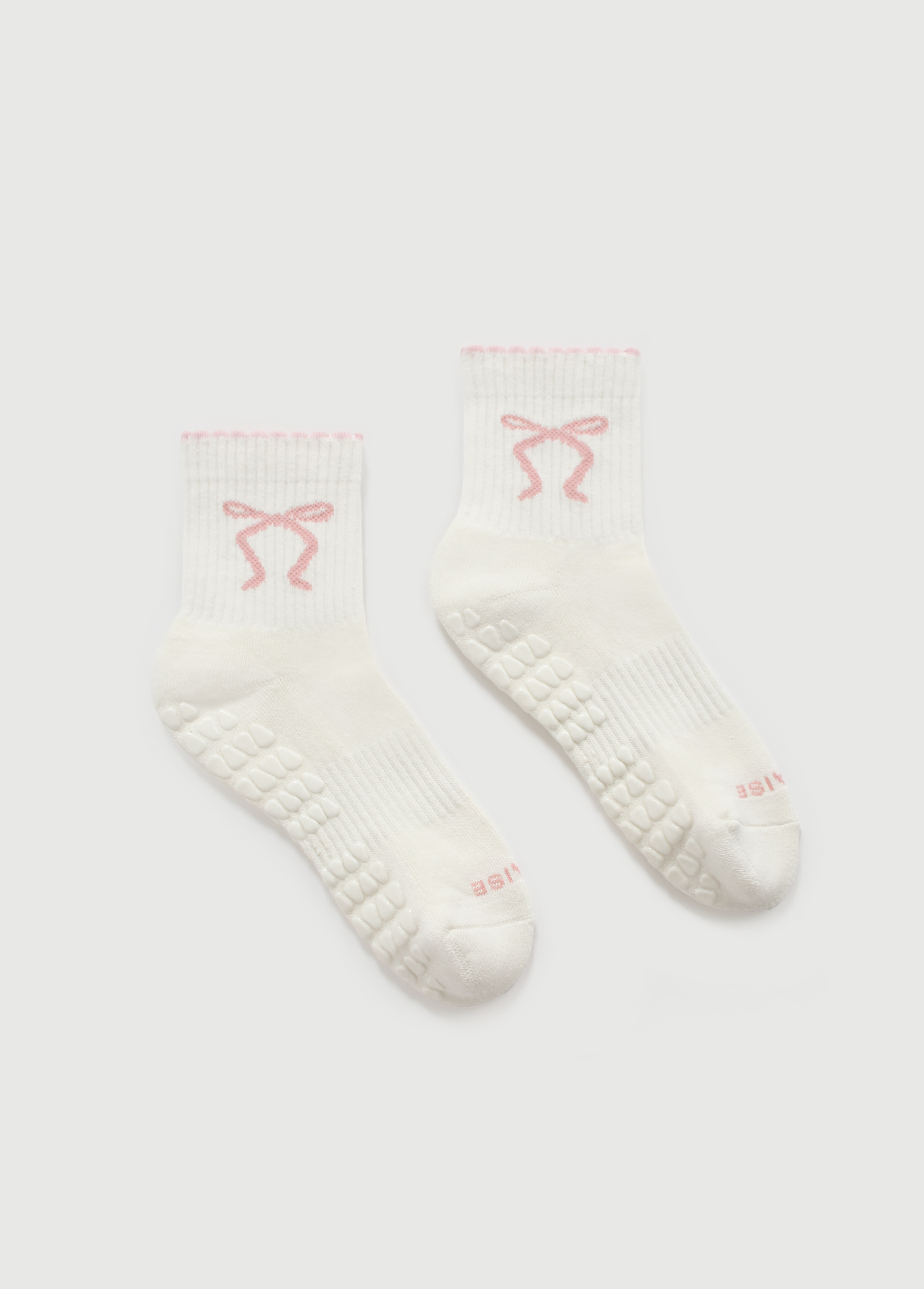 Fraise pilates grip socks with pink bows on them, laid flat.