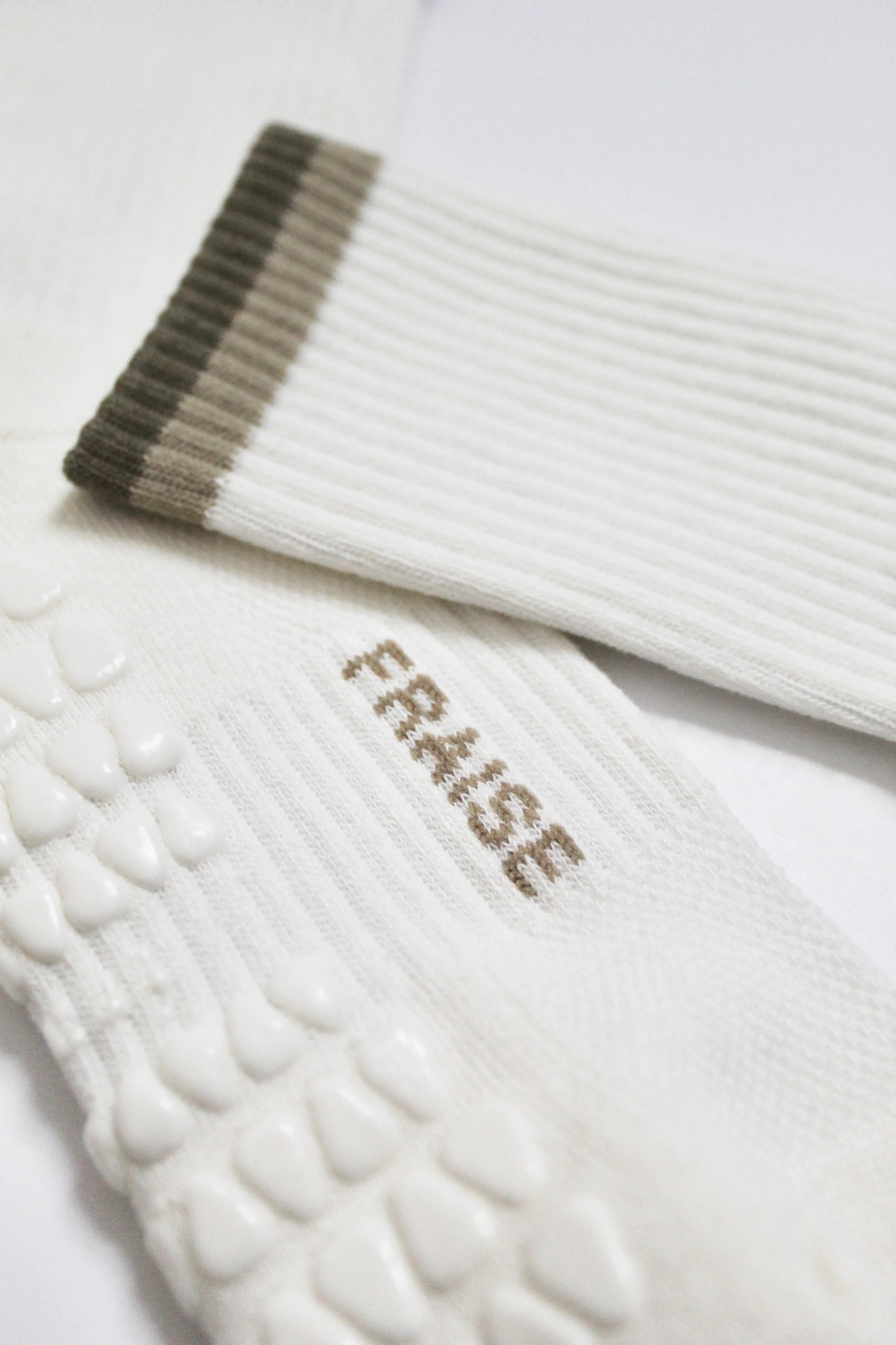 White pilates grip socks with green ribbed cuffs and 'FRAISE' branding on midfoot