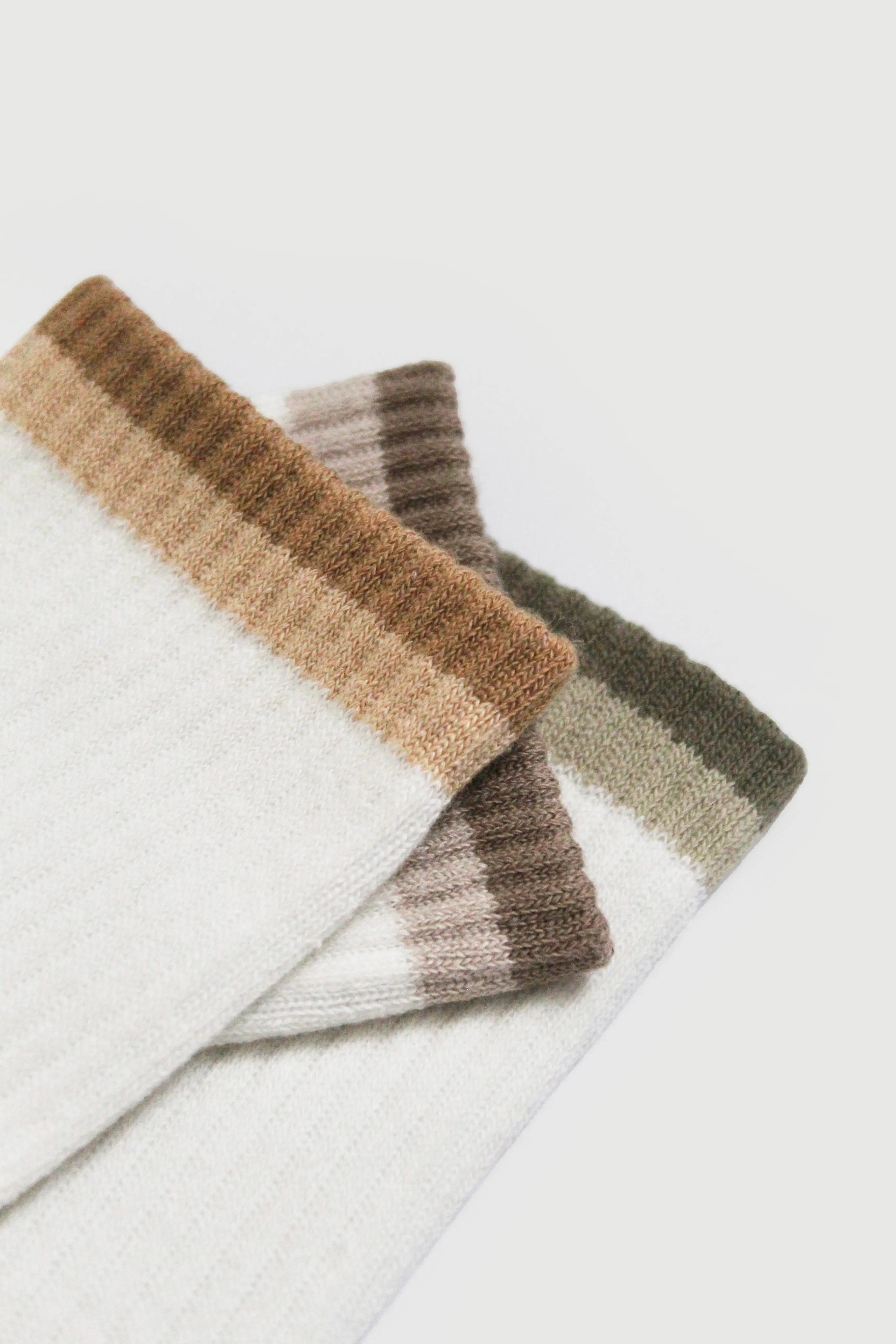 Stack of striped pilates grip socks in brown, beige, and white on a light gray background