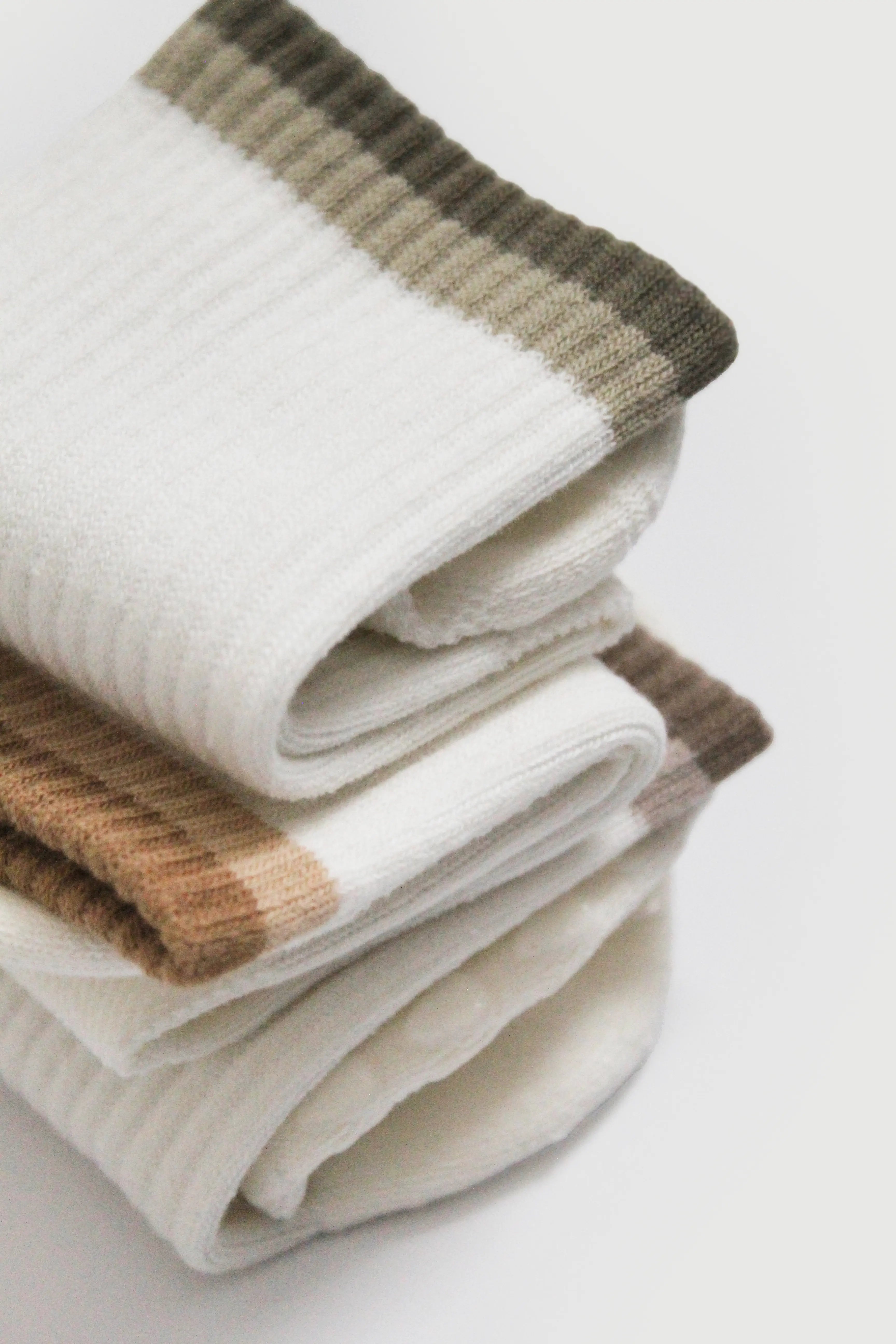 Stack of folded beige and brown striped pilates grip socks on a white background