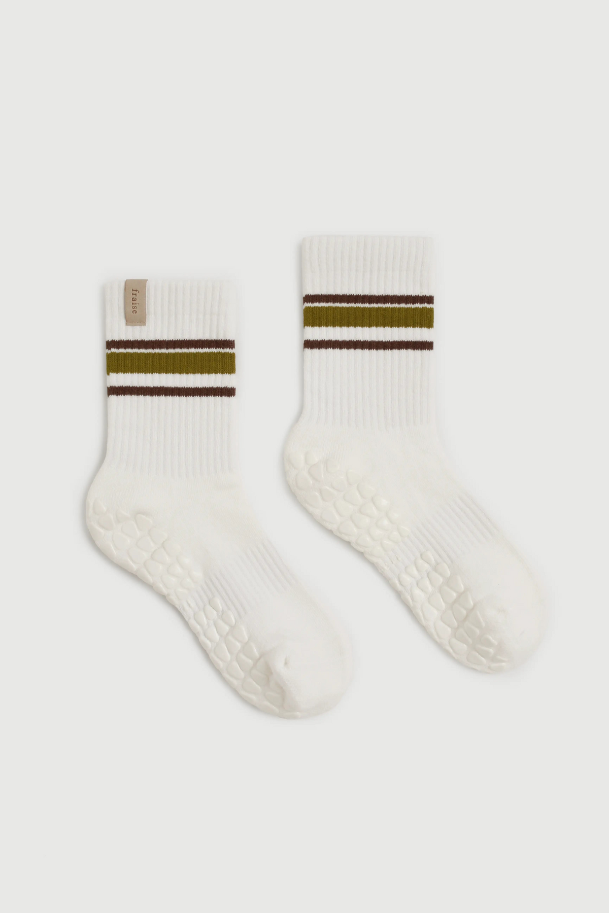 A pair of white ribbed crew socks with textured grip soles, featuring a double stripe design at the cuff with olive green and dark brown bands, shown on a light gray background.
