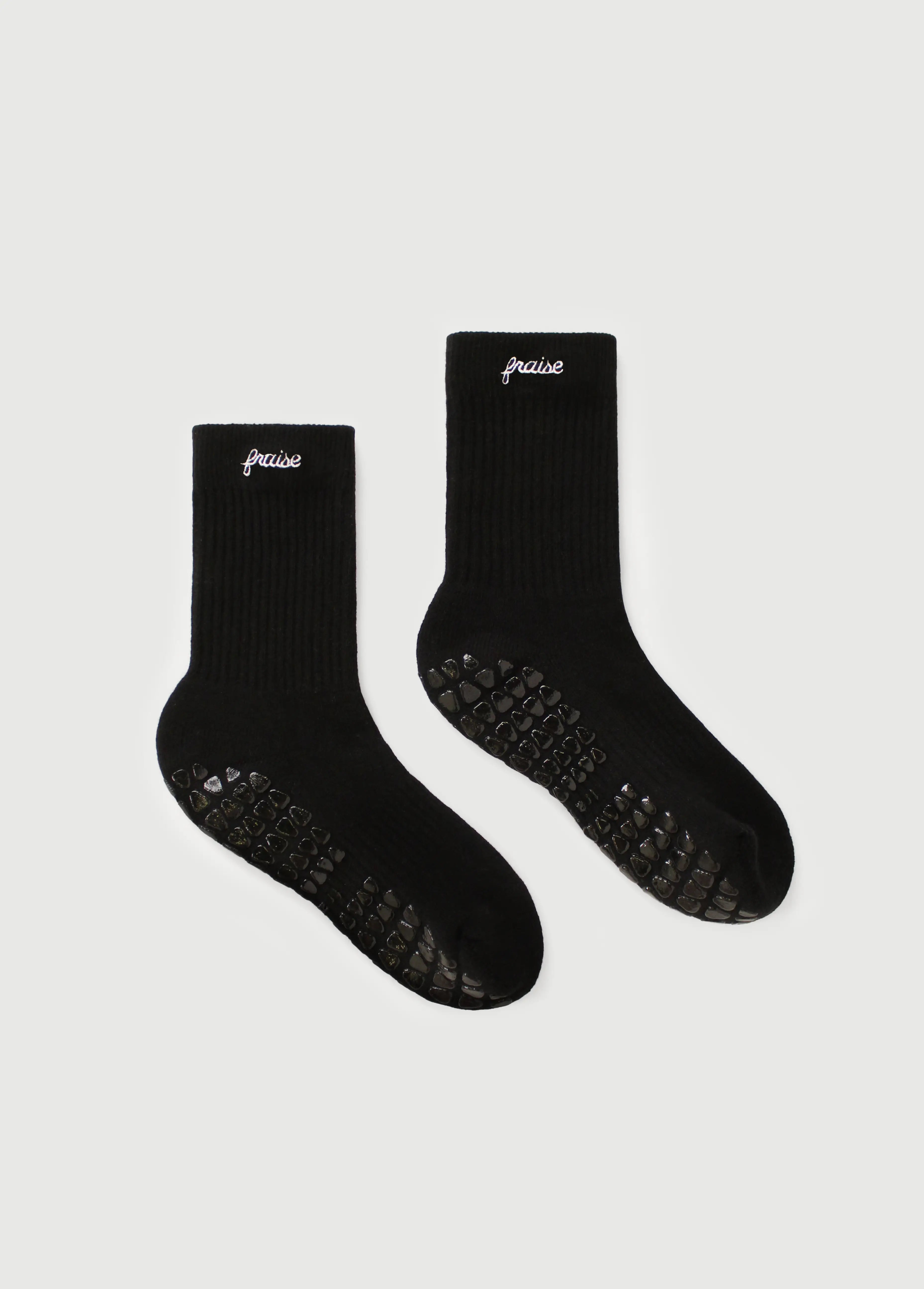 Two black grip socks for the reformer, with textured grip soles and the brand "Fraise" embroidered in white on the cuff, displayed on a light gray background.