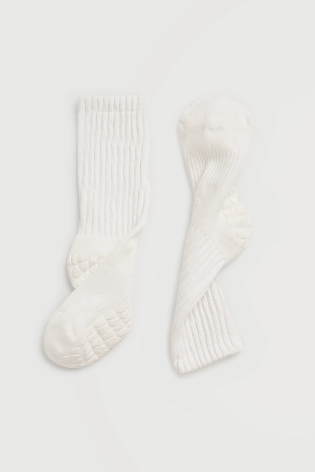 A pair of off-white ribbed grip socks displayed flat against a light gray background for pilates, yoga, and barre.