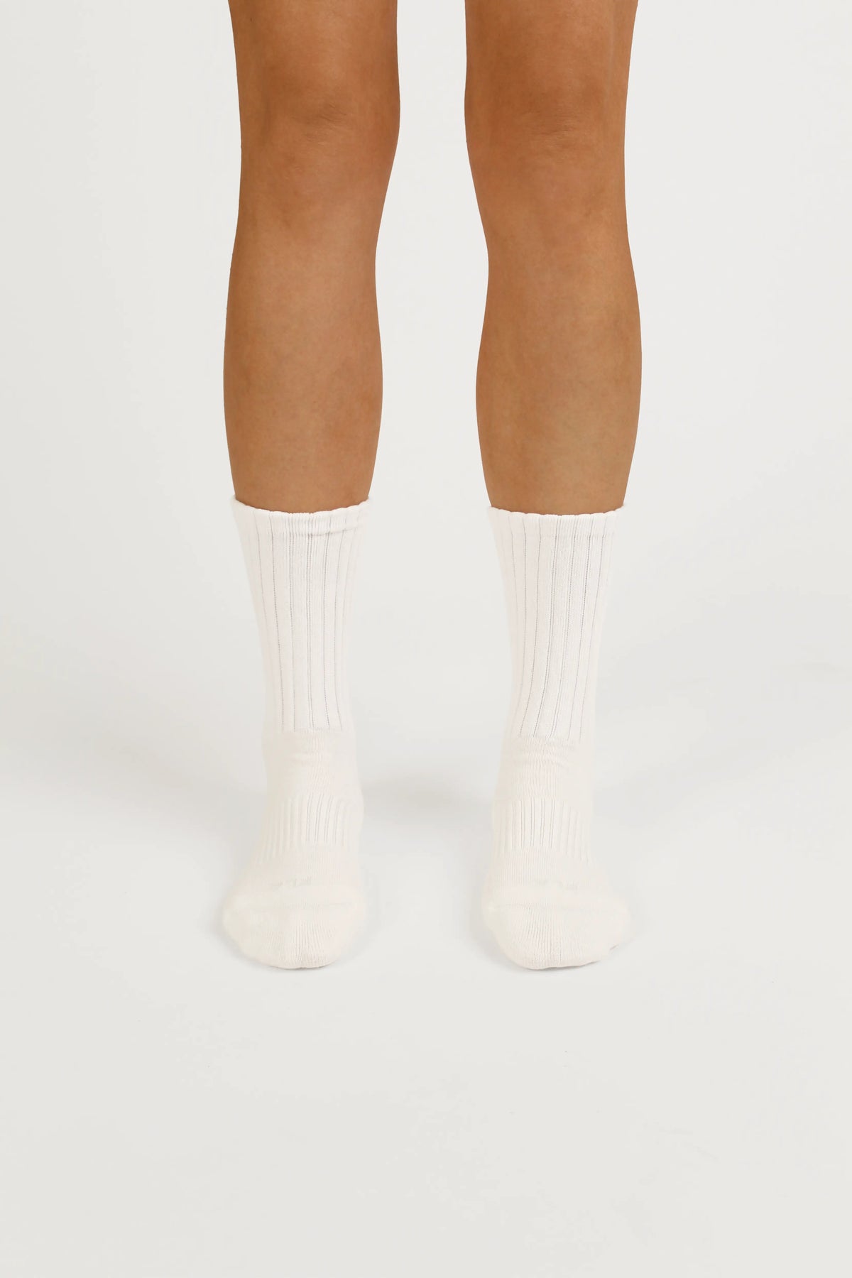 A pair of ribbed yoga socks worn on a person's feet, shown from the toes up against a clean, light off-white studio background.