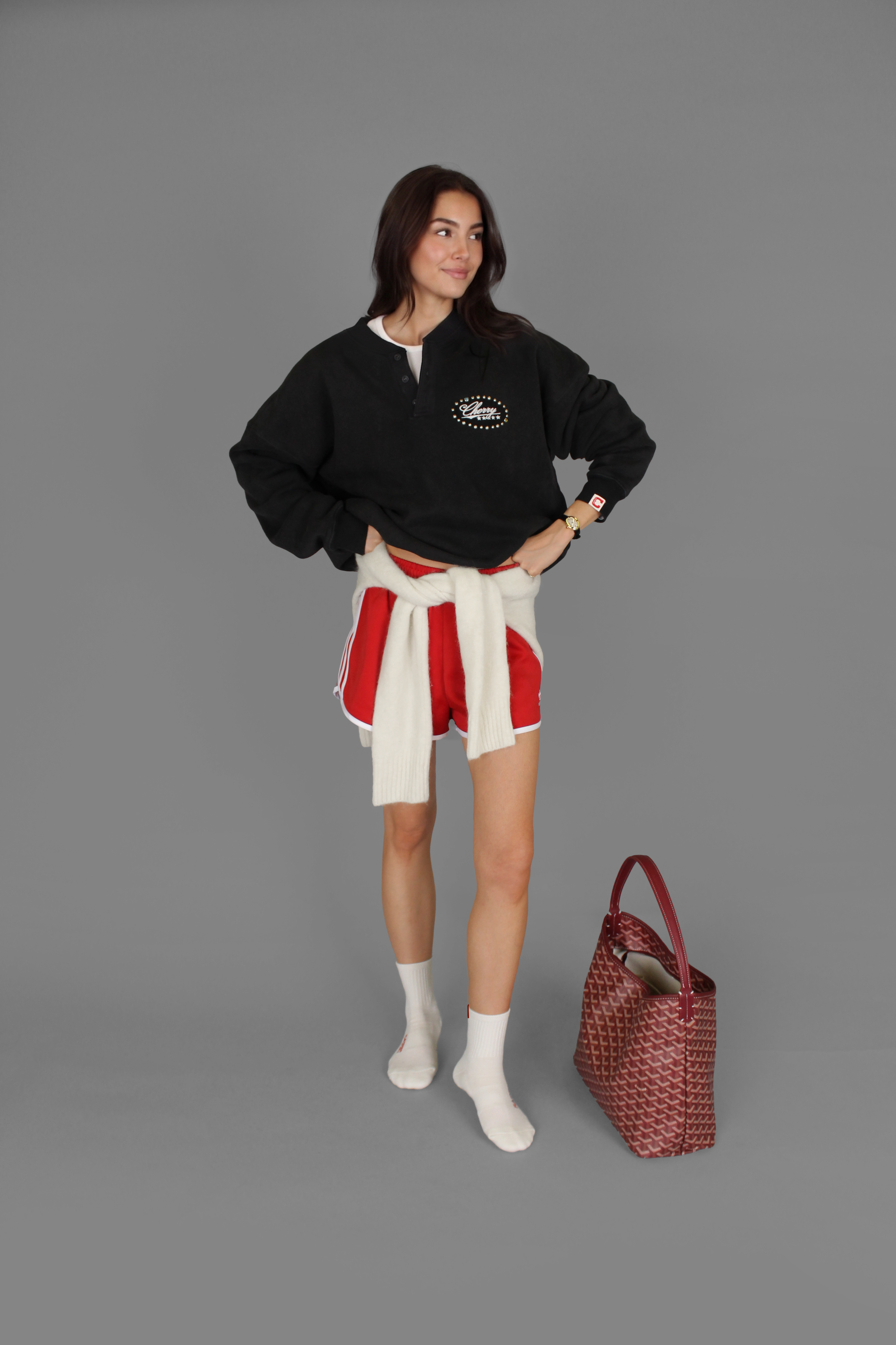 Model wearing black sweatshirt, red shorts, and white grip socks for pilates
