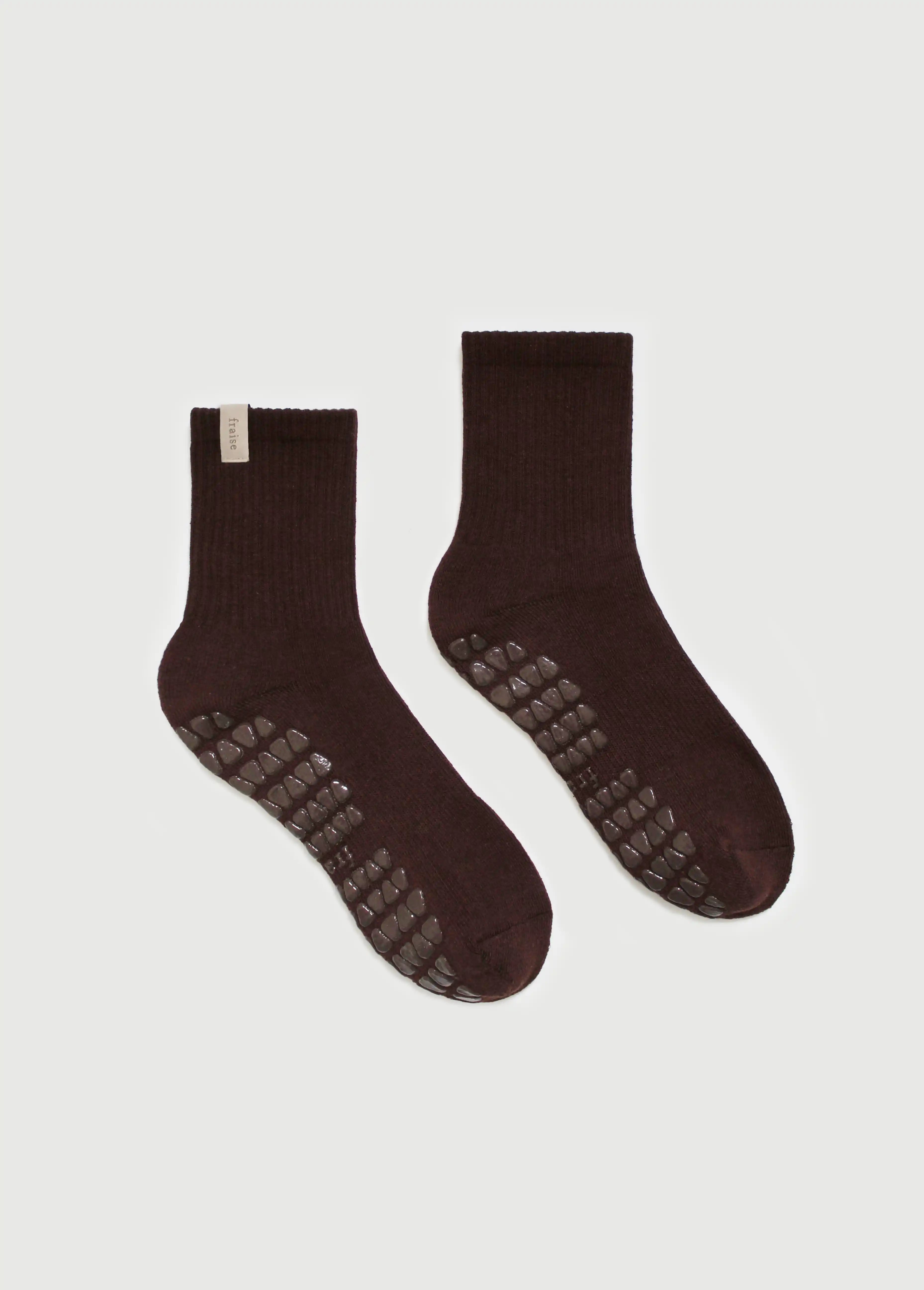 A pair of dark brown yoga crew grip socks with textured grip patterns on the soles, displayed against a light gray background.