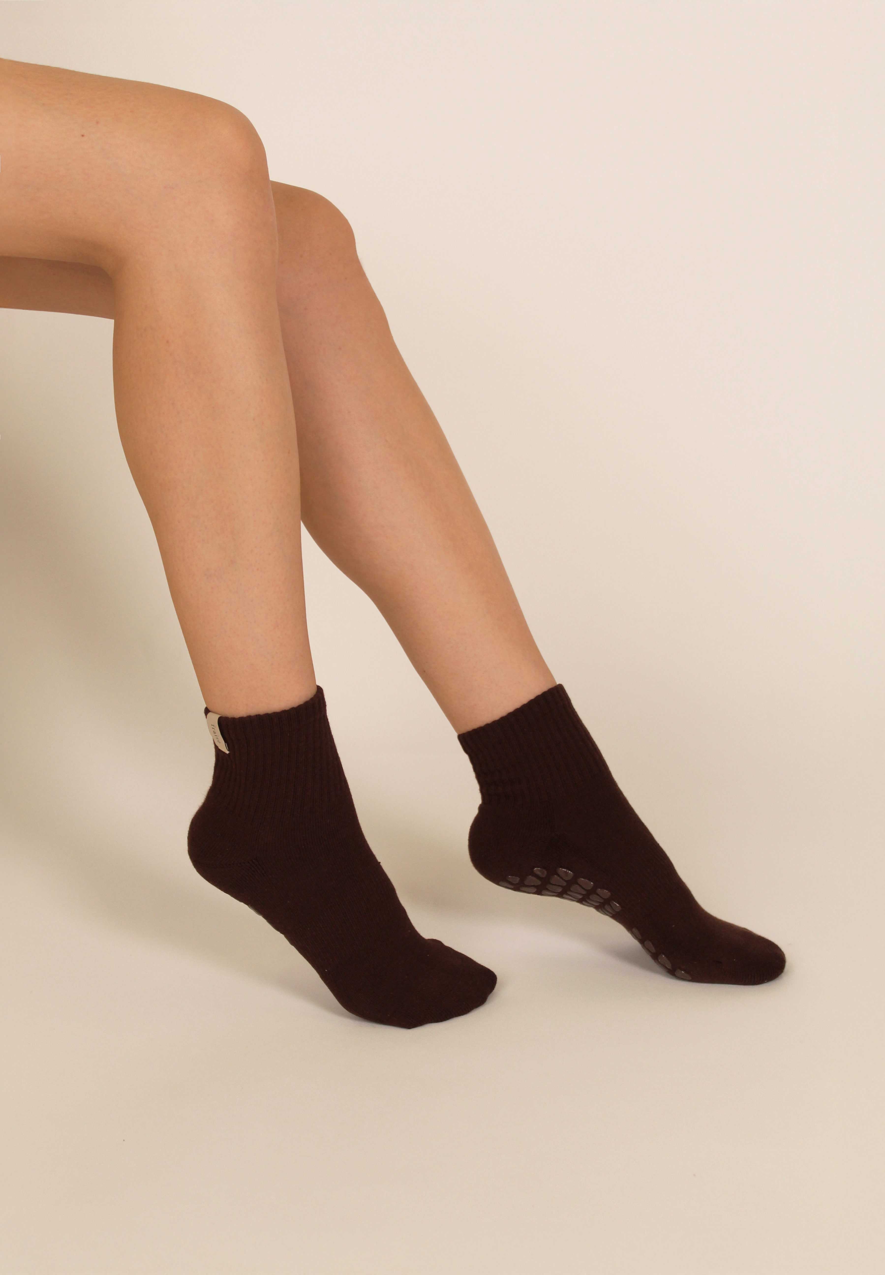 Person wearing espresso brown pilates grip socks on a beige background