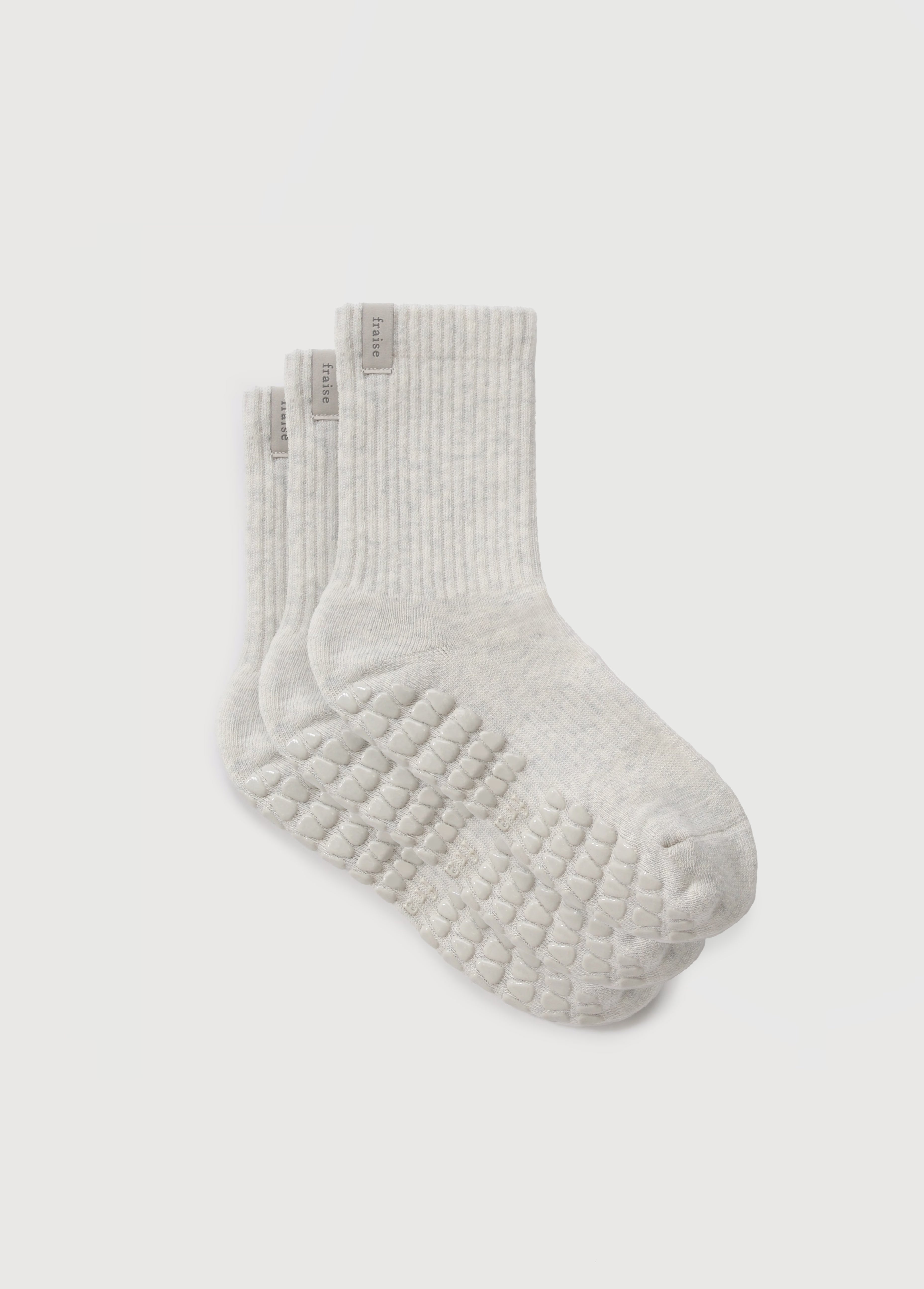 Trio of heather oat colored pilates socks from Fraise, with a Fraise label on the ankle. 