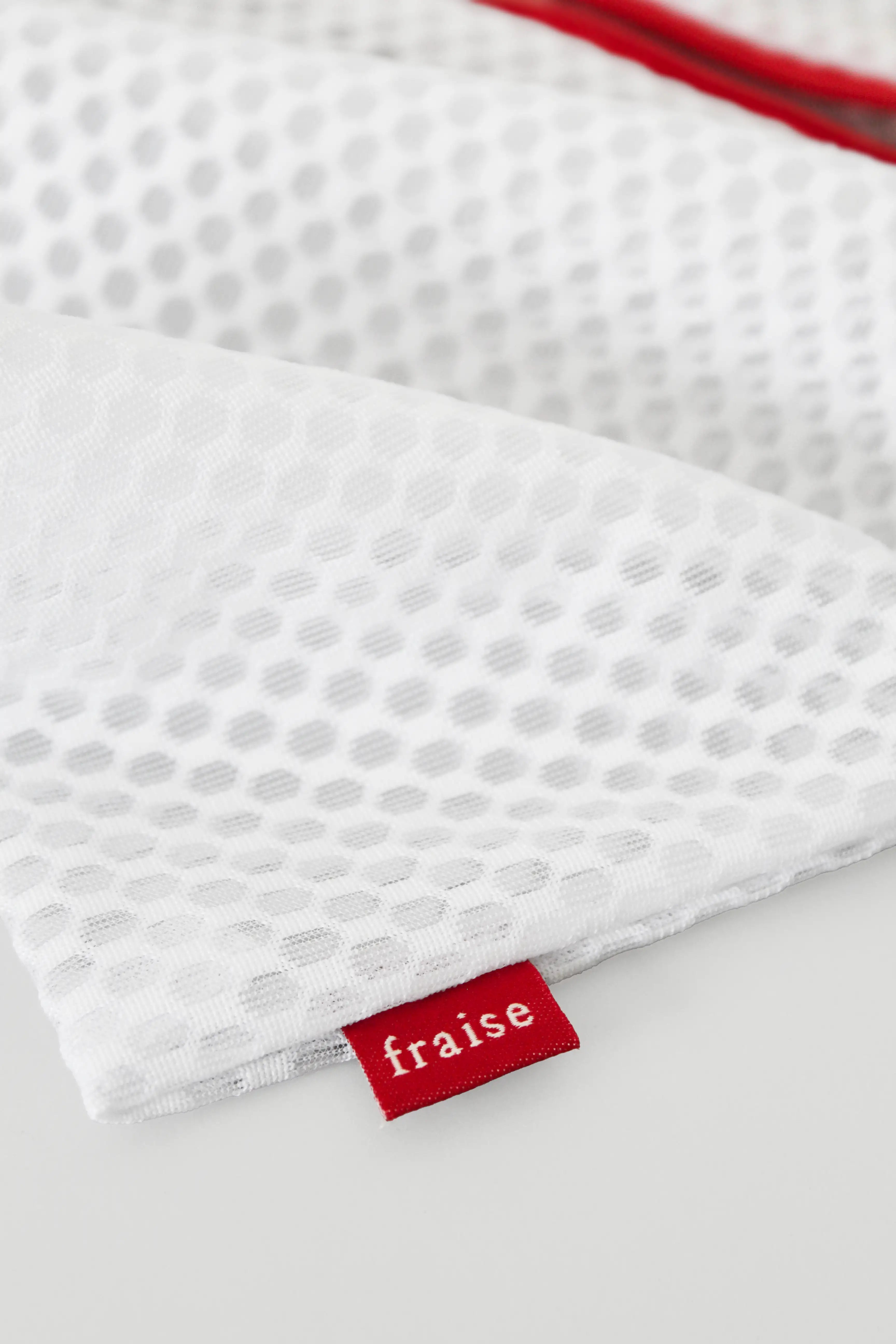 Mesh Fraise laundry bag with a red zippered pocket and a red brand tag