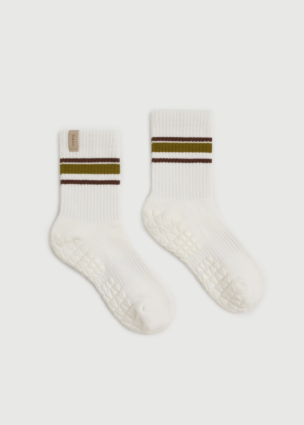 A pair of white Fraise yoga grip socks with textured grip soles, featuring a double stripe design at the cuff with olive green and dark brown bands, shown on a light gray background.