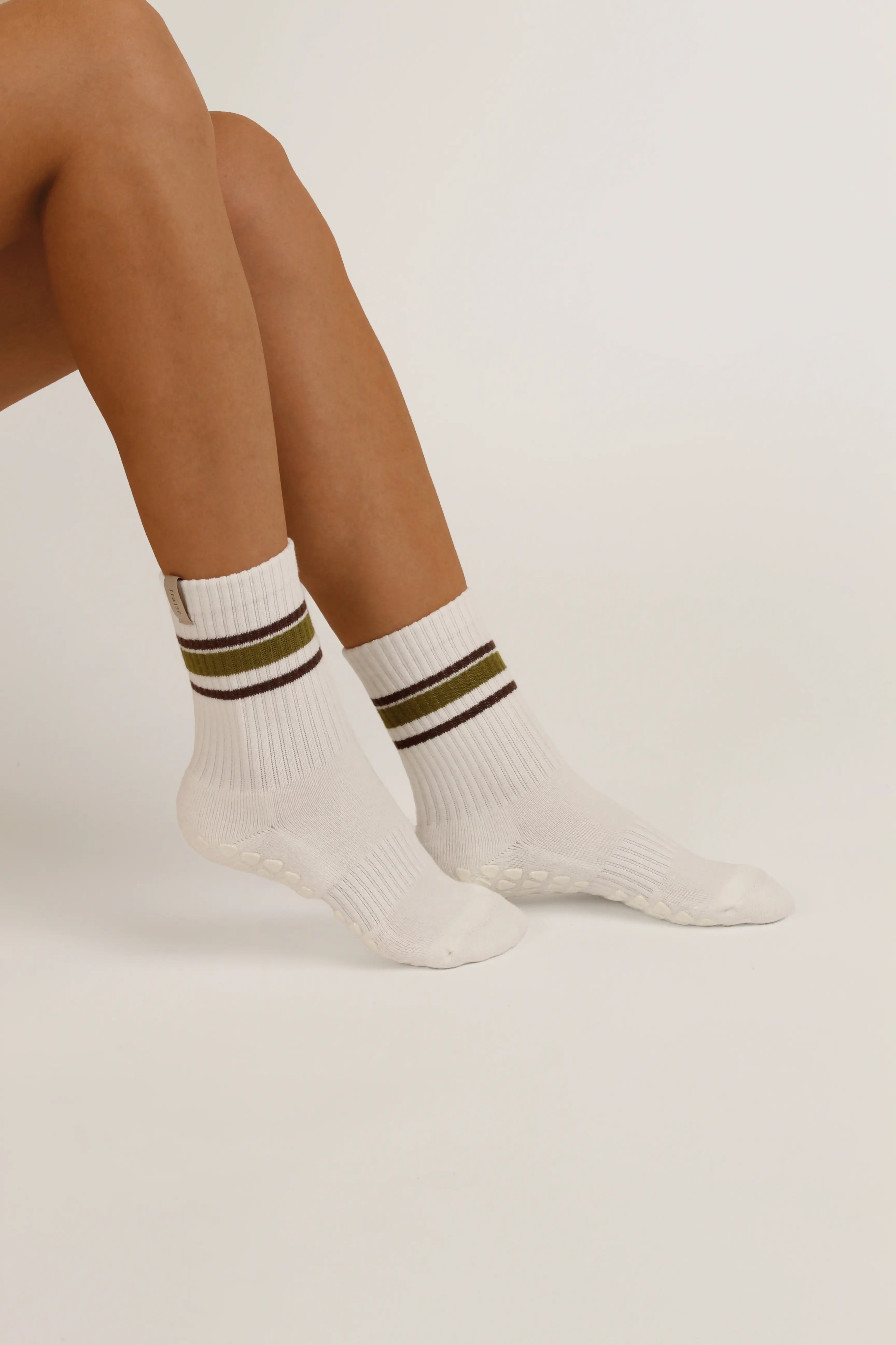 White Fraise reformer socks with olive green and dark brown stripes near the cuff, worn on a model's feet against a plain light background.