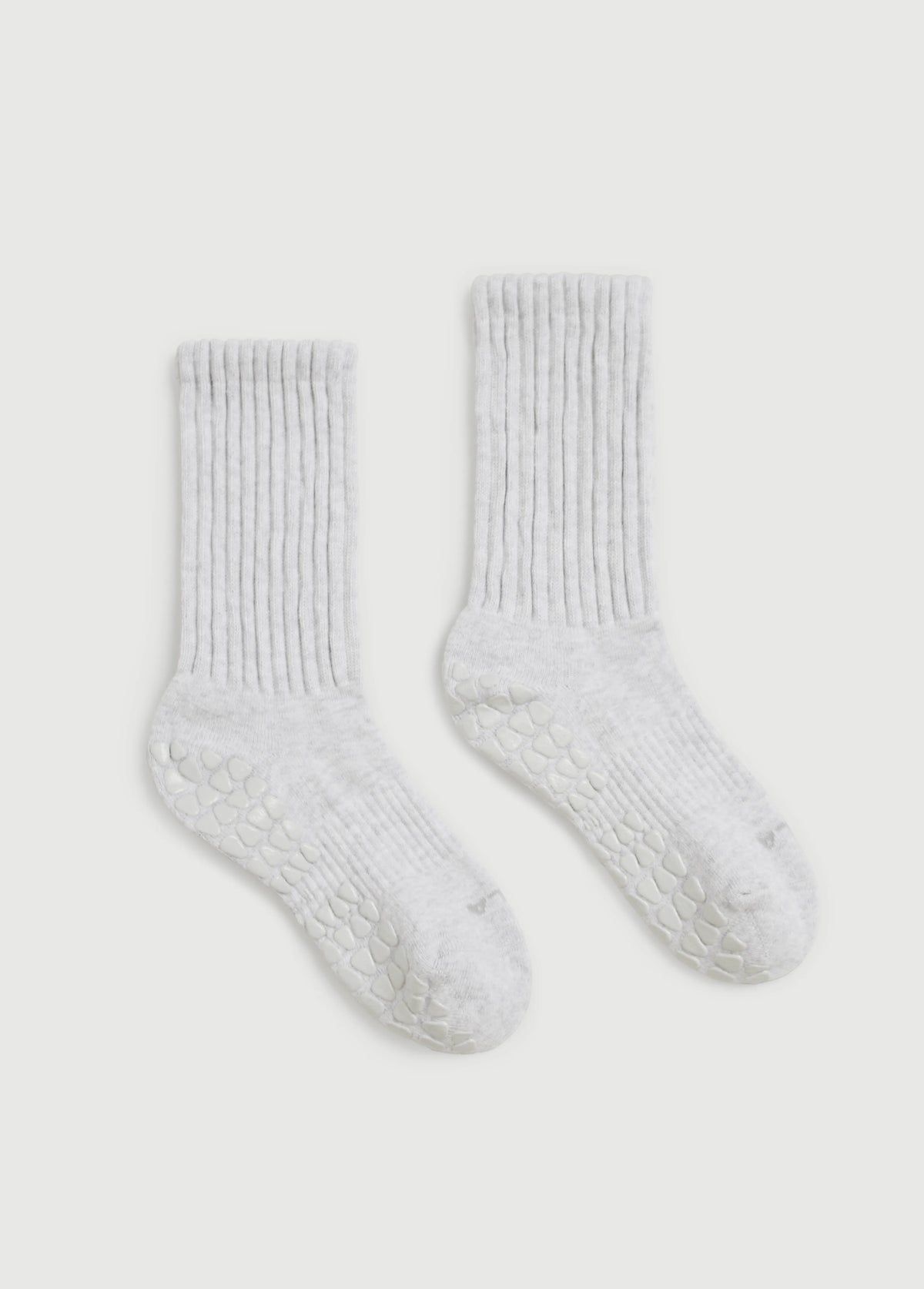 A pair of off-white ribbed grip socks with textured grip soles, displayed on a light gray background.