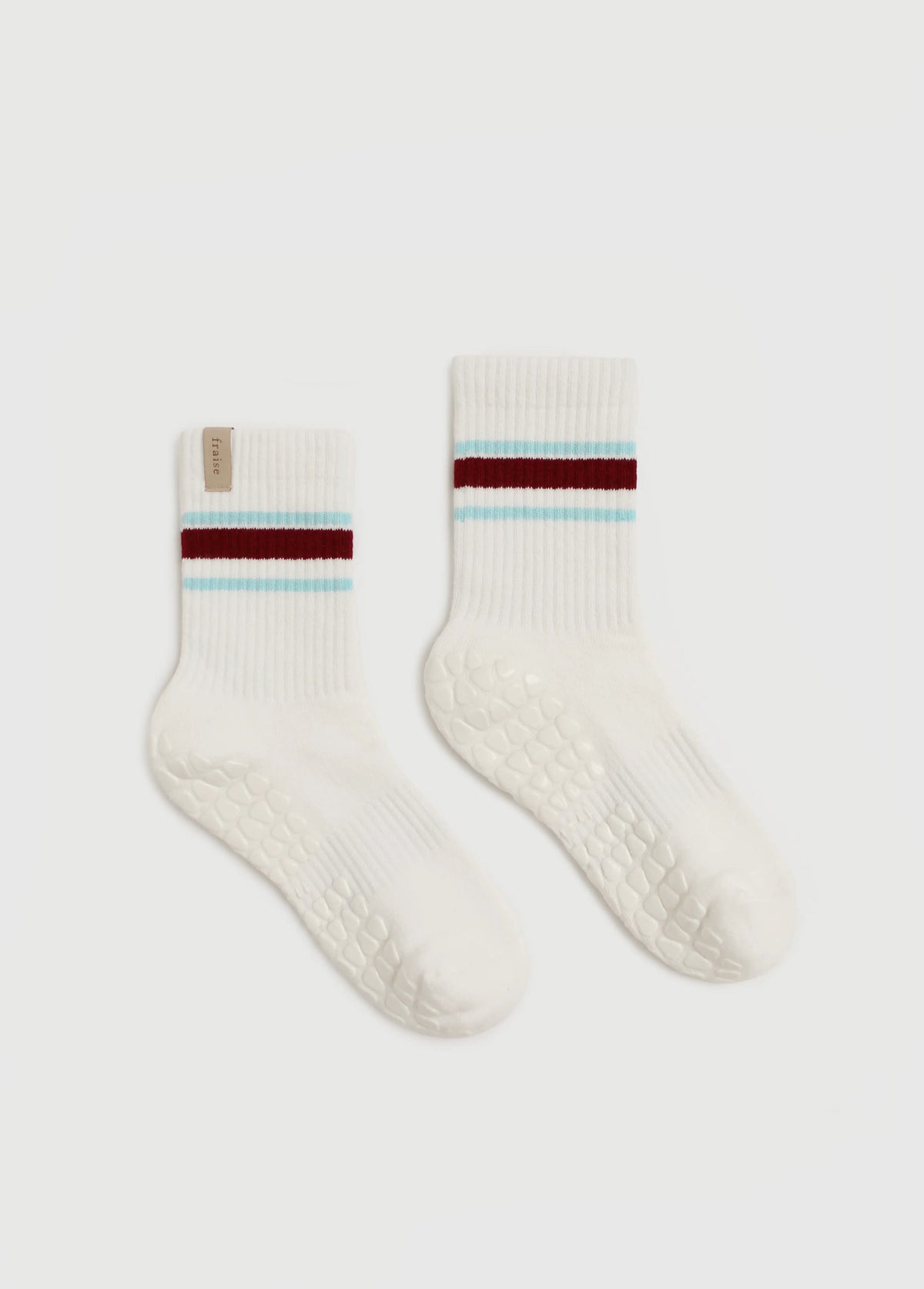 Fraise striped blue and burgundy grip socks for yoga, pilates, and barre on top of a reformer.