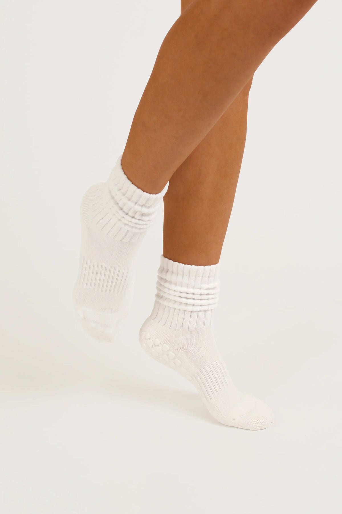 White yoga grip socks worn on a model's feet, shown against a clean white studio background.