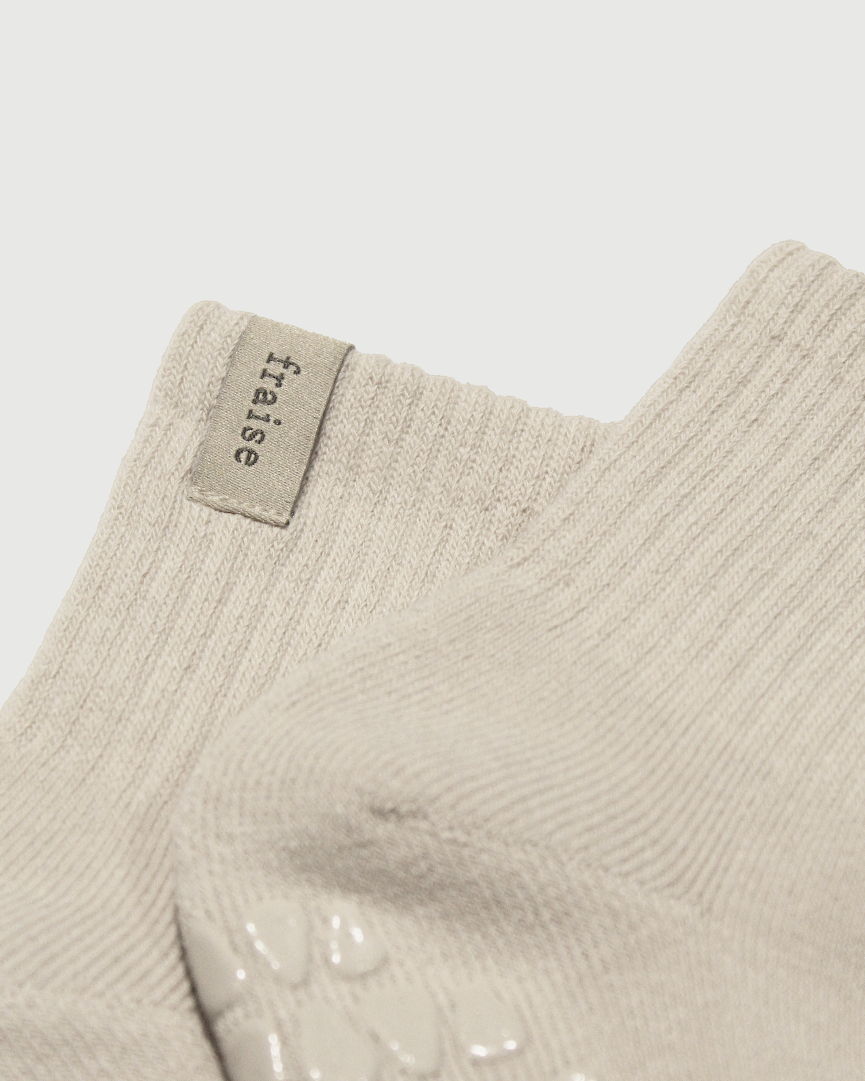 Close up of beige sock with 'fraise' label on a light gray background