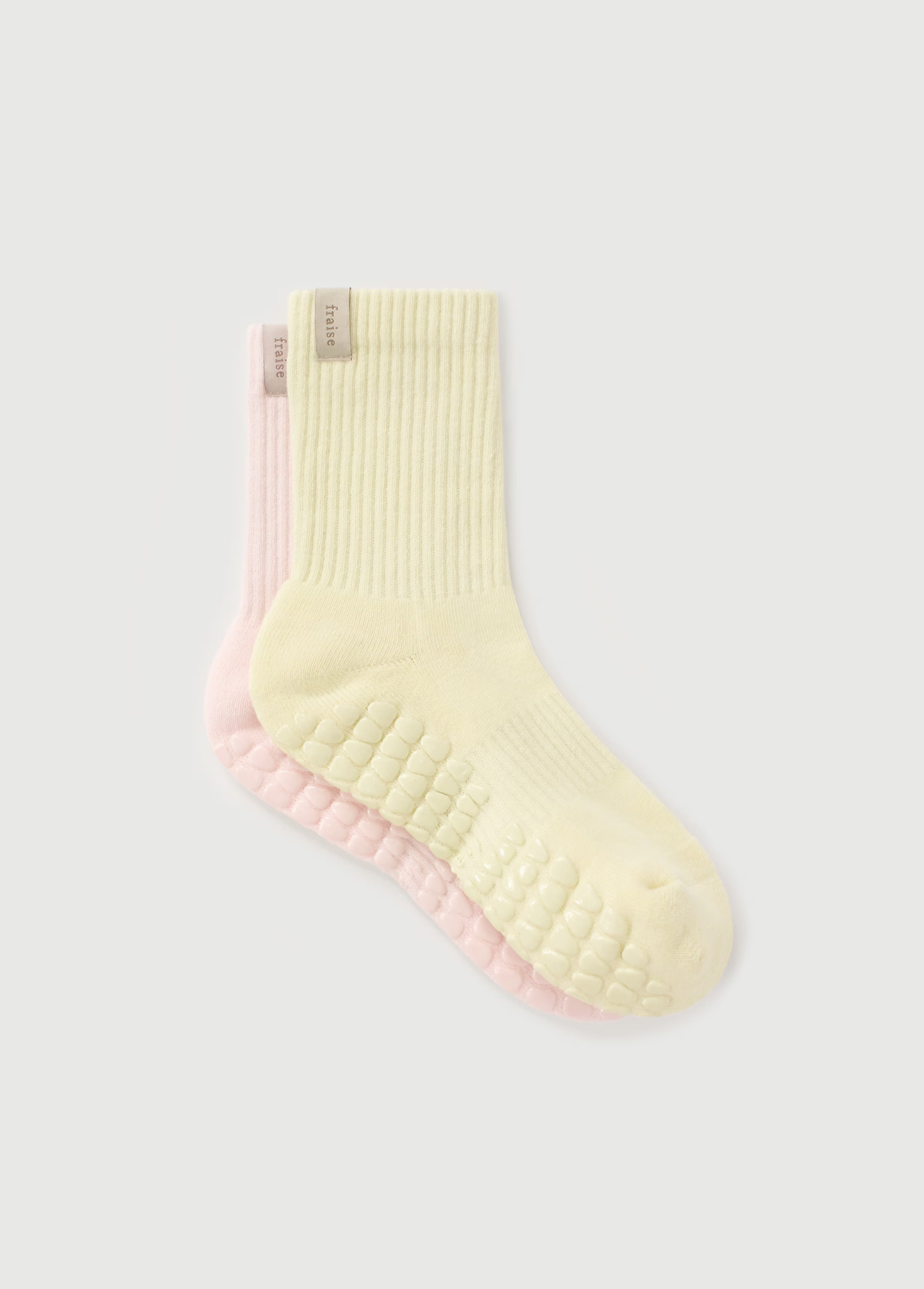 A pair of yellow and pink pilates reformer grips socks.