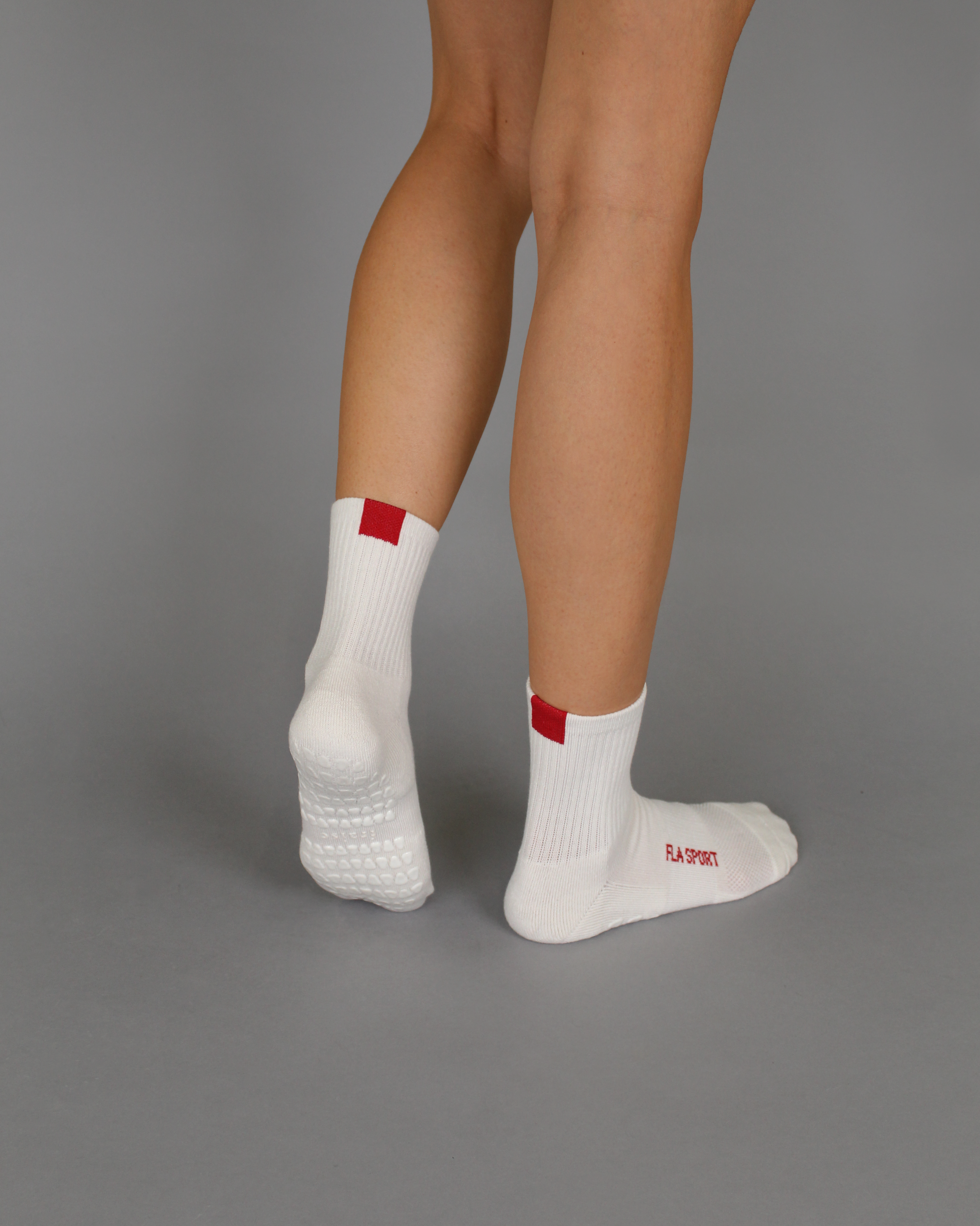model wearing white grip socks with red tab and FLA SPORT text