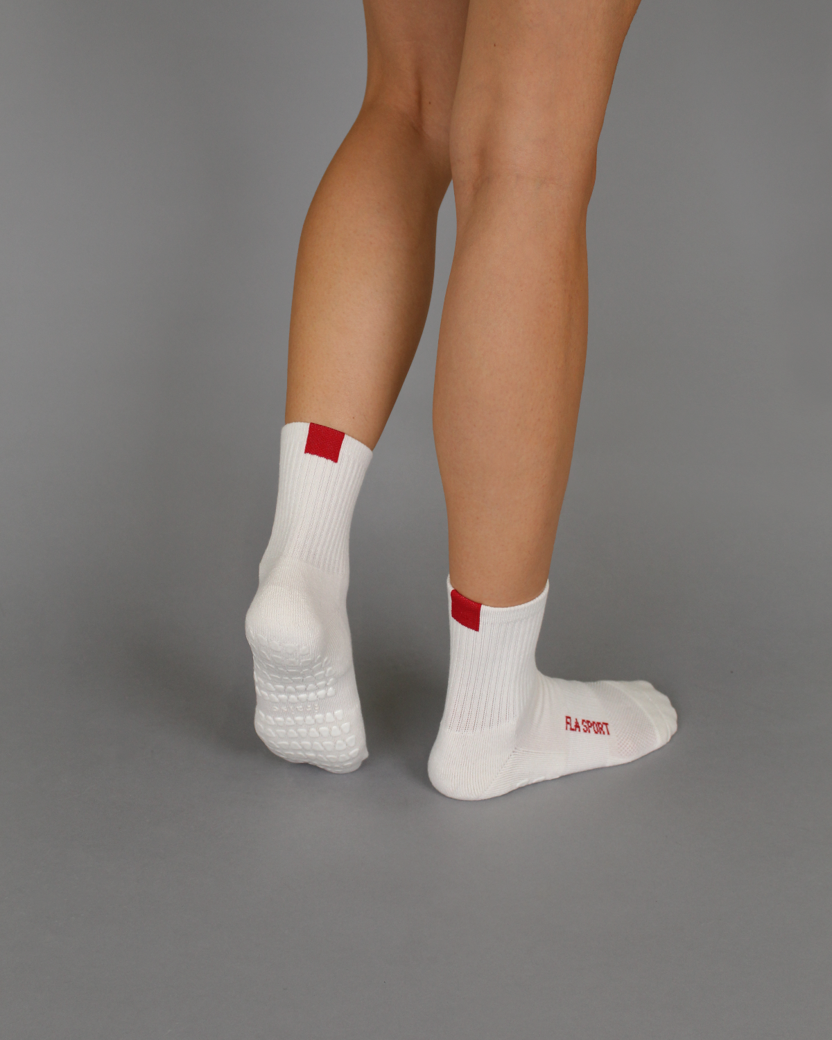 model wearing white grip socks with red tab and FLA SPORT text